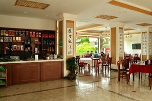 Un hall de hotel con una recepción, zona de comedor y un amplio ventanal.