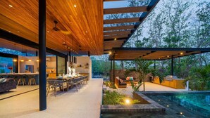 Un espace de vie extérieur moderne doté d’une piscine, d’un coin repas et d’une cuisine.