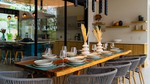 Un coin repas avec une longue table en bois, dressée pour six personnes, entourée de chaises en osier.