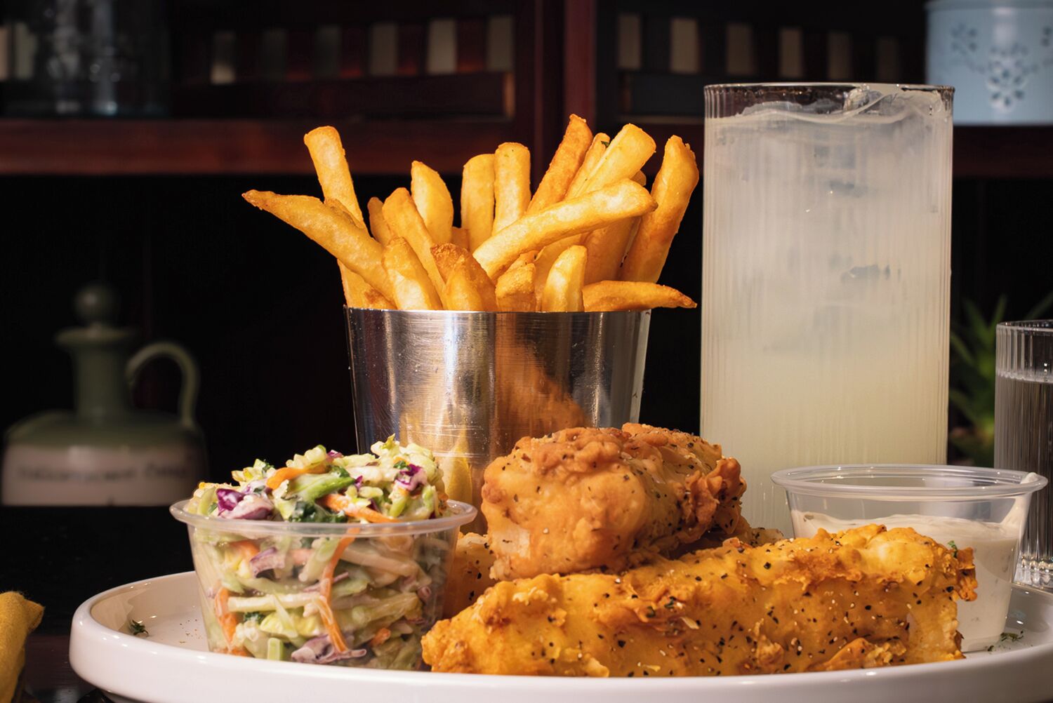Une assiette de poulet frit, de frites, de salade de chou et une boisson.