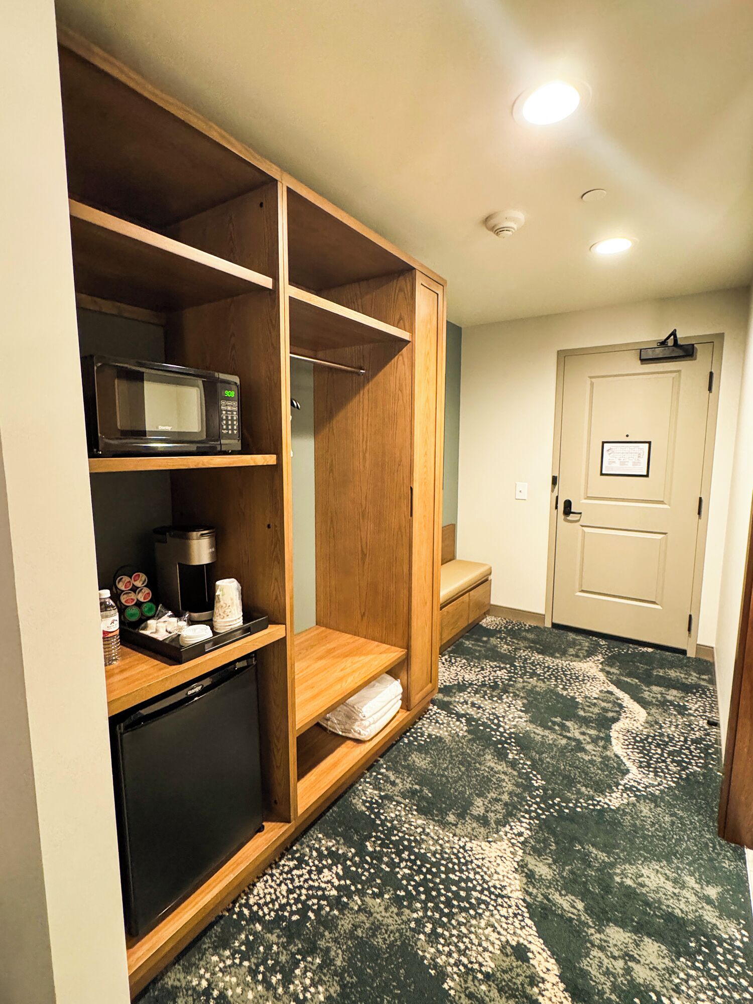 Ein Hotelzimmer mit einem Holzschrank, einer Mikrowelle, einer Kaffeemaschine und einem kleinen Kühlschrank.