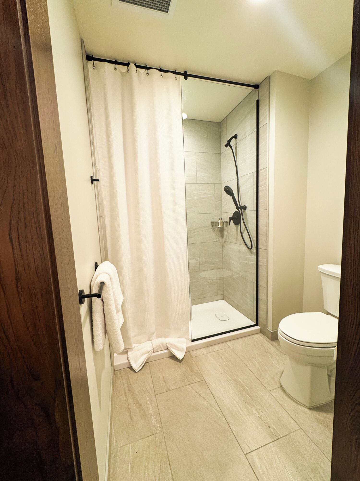 A modern bathroom with a glass-enclosed shower, a toilet, and a towel rack.