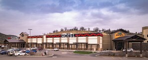 A hotel with a prominent 'HOTEL' sign, a parking lot with several cars, and a mountainous backdrop. - Rain Rock Casino Resort Hotel (Yreka)