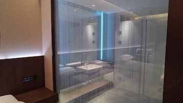 Un baño moderno con separador de vidrio, tocador de madera y zona de ducha.