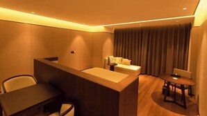 Habitación de hotel con mostrador de recepción, sofá, mesa de comedor y una cortina.