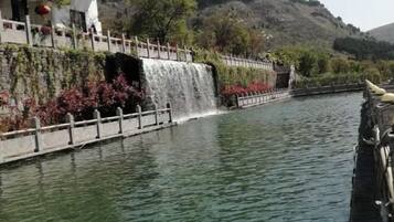 Un río tranquilo con cascada, un puente y un edificio de fachada blanca.