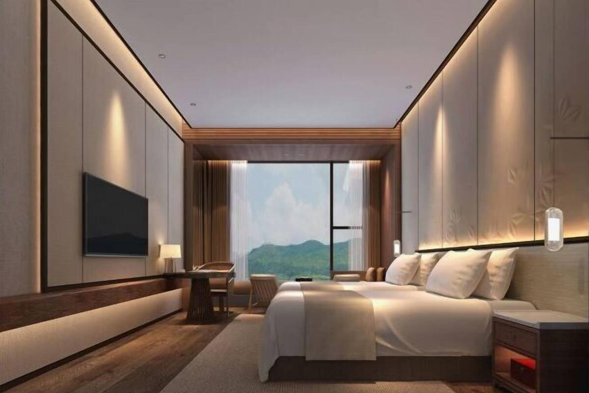 Una habitación de hotel moderna con una cama grande, un escritorio y vistas a las montañas.