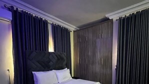 Un dormitorio con una cama grande, cortinas oscuras y un armario.