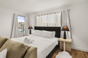 Une chambre d’hôtel avec un lit, deux tables de chevet avec des lampes, une fenêtre avec des rideaux et une vue sur les bâtiments environnants.