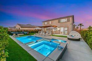 Une maison moderne dotée d’une piscine, d’un espace salon extérieur et d’un patio.