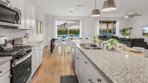 A modern kitchen with granite countertops, stainless steel appliances, and pendant lighting. - 15 Bed, Glow Gameroom, Putting green, Pool & BBQ (Coachella)