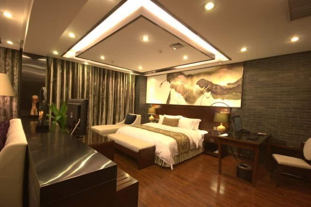 A modern hotel room with a large bed, a desk, and a TV.