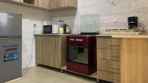 A kitchen with wooden cabinets, a refrigerator, a microwave, a stove, and a coffee maker. - 4mins to Aso-Rock Villa, King Bed, Chef, Free Cleaning, 24/7 Electricity  (Abuja)