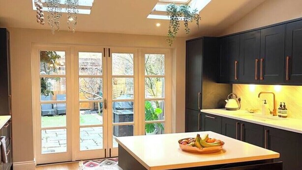 A modern kitchen with a central island, dark cabinetry, and a skylight. - A sun-kissed, cozy family home. (London)