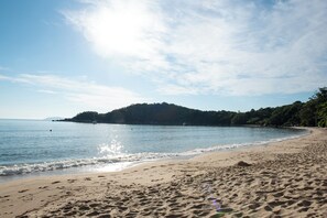 Una playa con cielos despejados, agua tranquila y una orilla arenosa.
