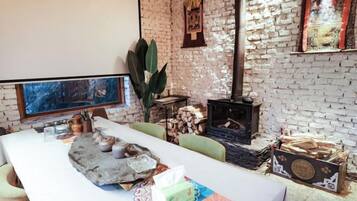 Una habitación con una mesa larga, una chimenea y un ventanal amplio.