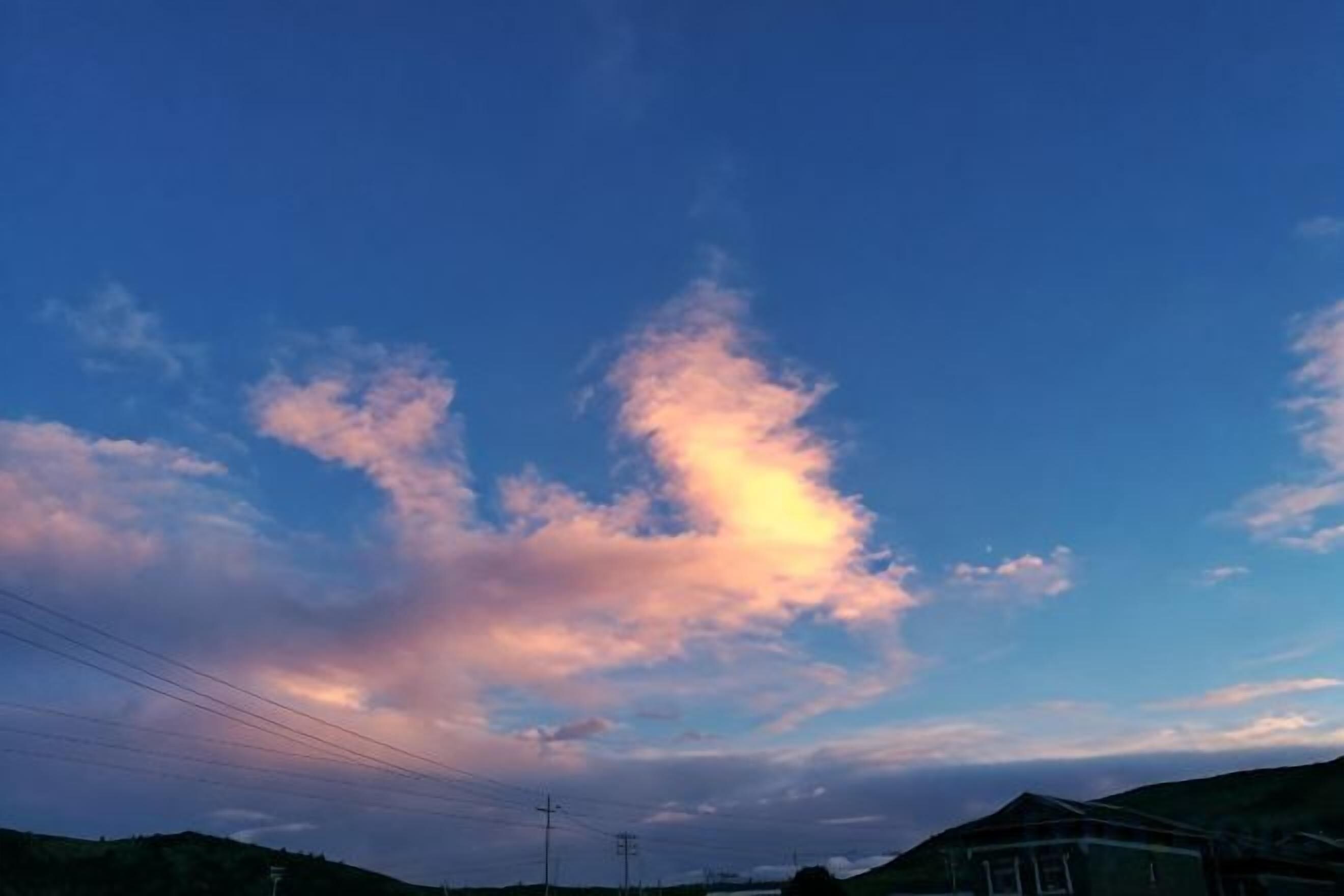 A clear sky with clouds and power lines.