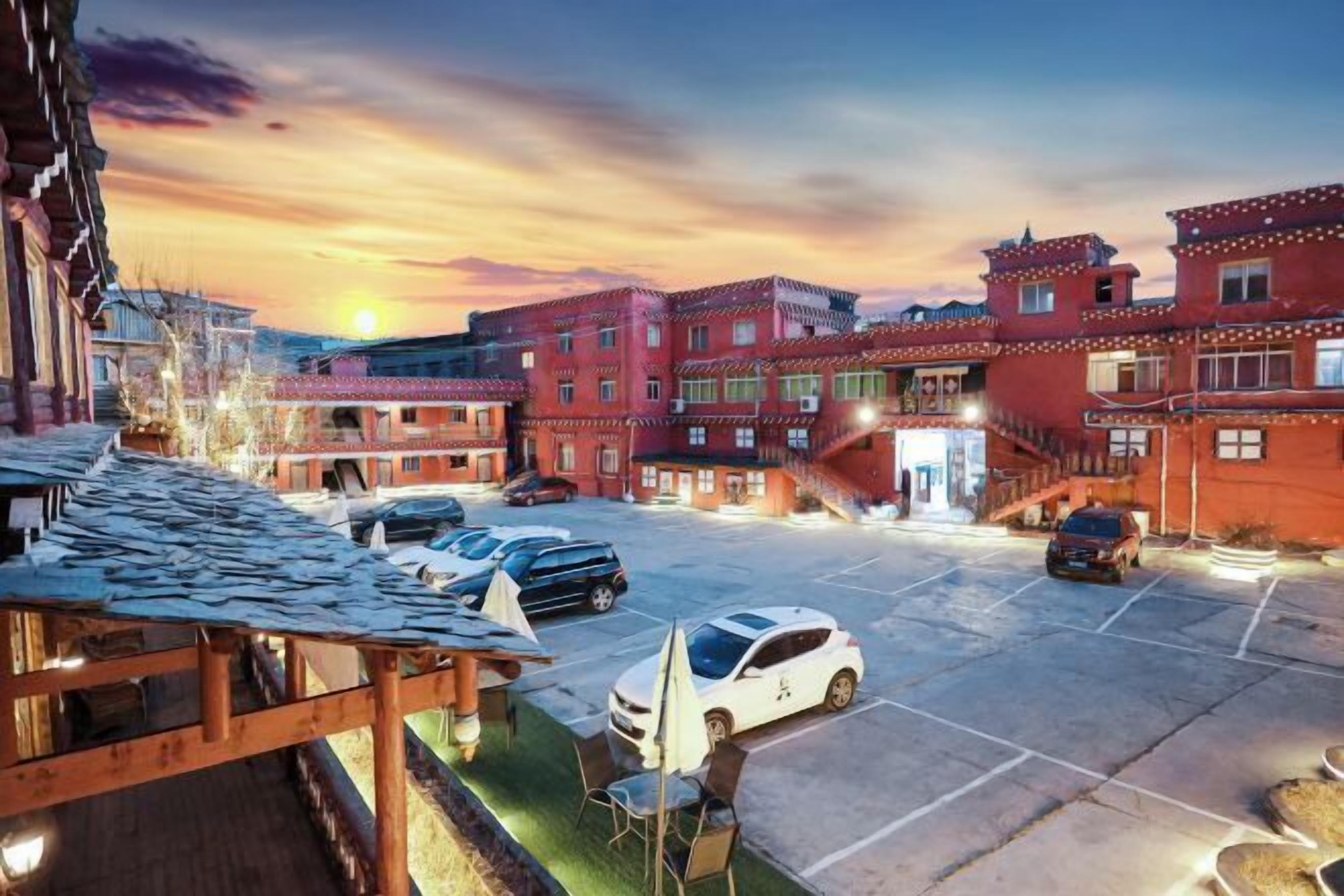 Ein Innenhof mit Holzterrasse, einer überdachten Sitzgelegenheit und einem Parkplatz mit mehreren Autos.