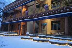 A two-story building with a balcony, a staircase, and a snow-covered ground. - Garze Tagong Grassland Hotel (Kangding)