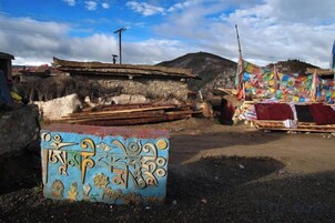Entorno rural con una edificación tradicional, una oración con banderines de colores y un letrero azul con caligrafía.