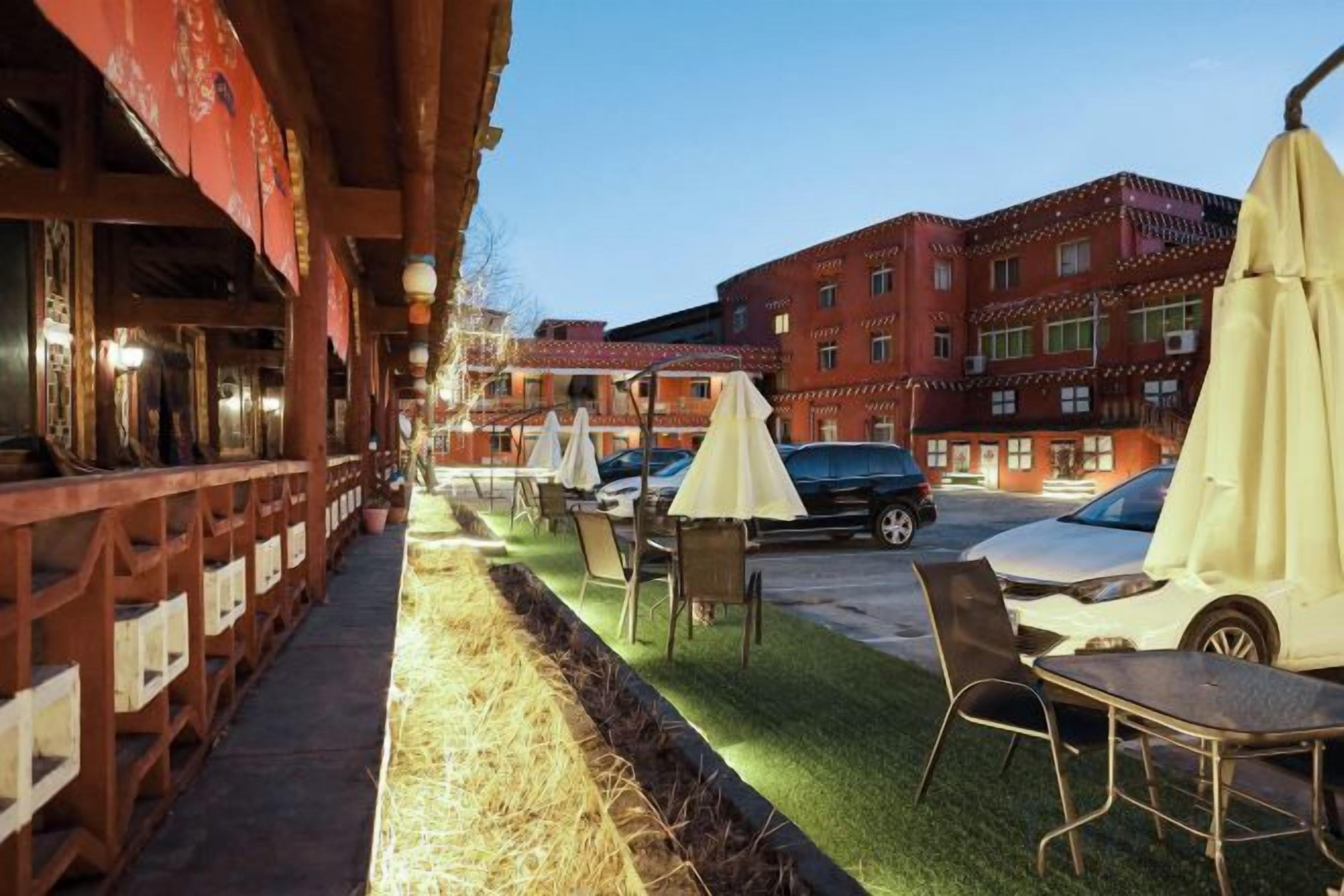 An outdoor seating area with tables and chairs, a covered walkway, and a building in the background.