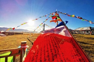 Una yurta tradicional con oraciones en banderas de colores y un cielo despejado.