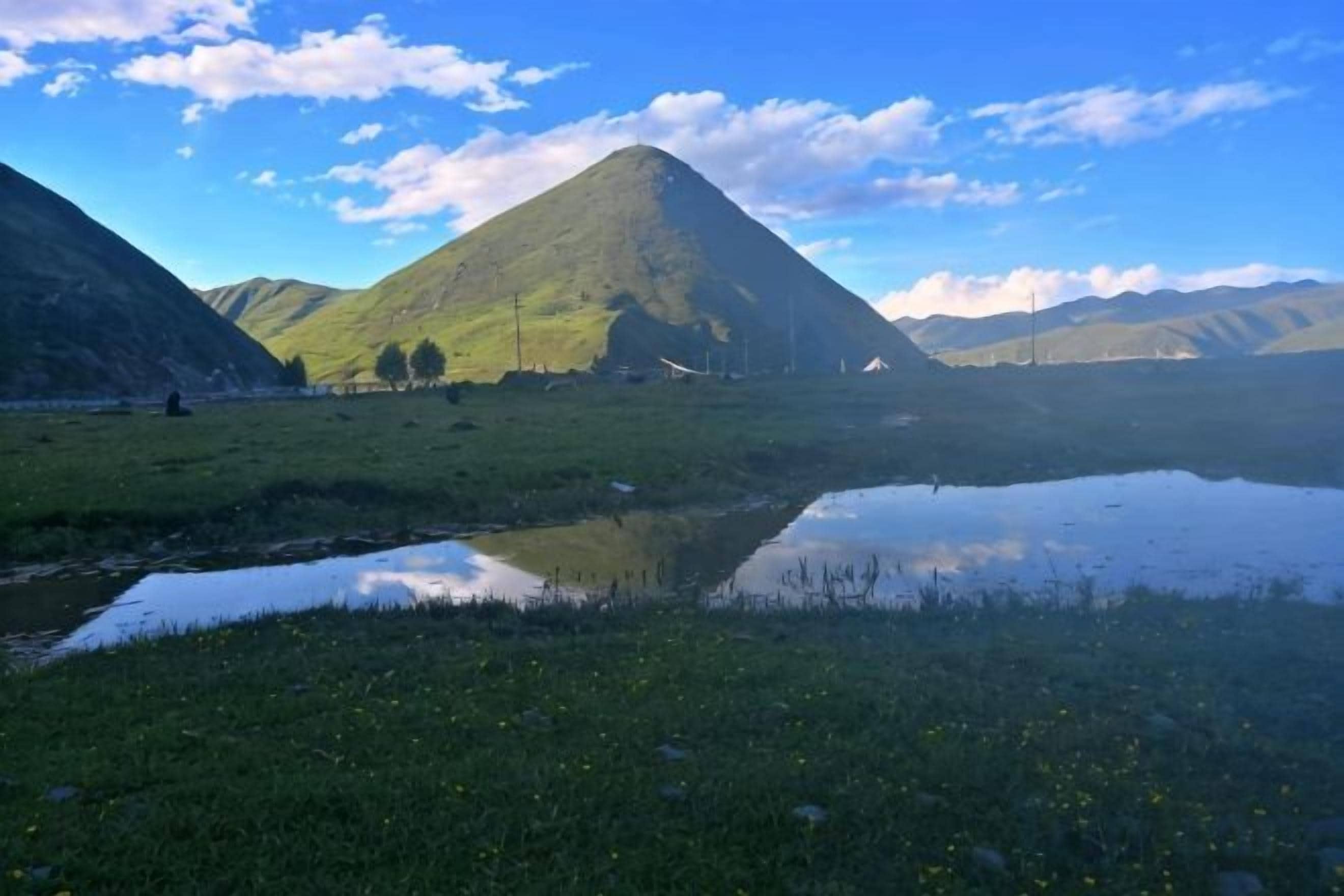 A mountainous landscape with a clear sky and a small body of water reflecting the surroundings.
