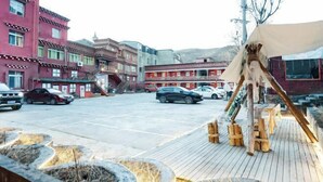 Vista de la calle con edificios, coches aparcados y una terraza de madera con una estatua de un caballo.