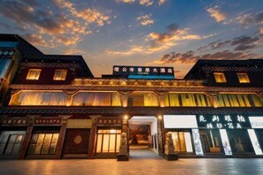 A traditional building with multiple storefronts, a prominent sign above the entrance, and a courtyard. - Garze Tagong Grassland Hotel (Kangding)