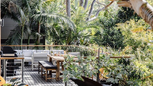 Une terrasse extérieure avec une table en bois, des bancs et un barbecue.