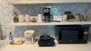Ett kök med mikrovågsugn, kaffebryggare och diverse köksredskap på bänkskivan.