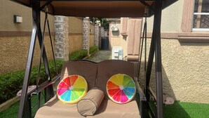 A swing set with a canopy, two cushioned seats, and a colorful circular design on the backrest. - 4mins to Aso Rock Villa, King Bed, Chef, Free Cleaning, 24/7 Electricity, Games (Abuja)