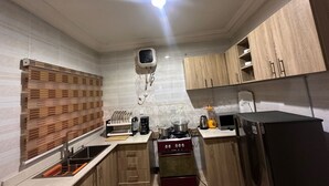 A compact kitchen with a stove, sink, and modern appliances. - 4mins to Aso Rock Villa, King Bed, Chef, Free Cleaning, 24/7 Electricity, Games (Abuja)