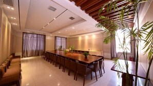 Una amplia sala de conferencias con una larga mesa y sillas, un sofá y una planta grande.