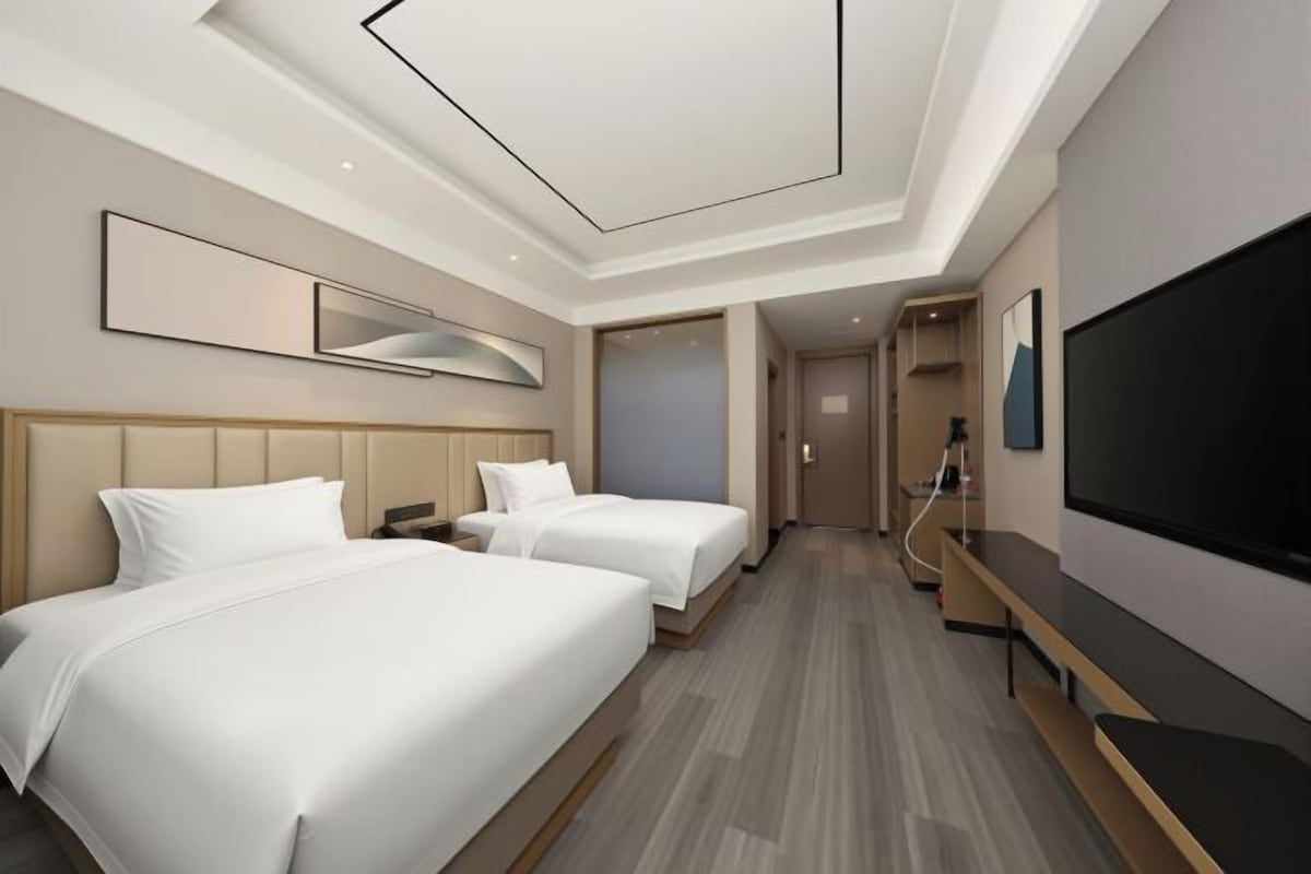 A hotel room with two beds, a flat-screen TV, and a modern design.