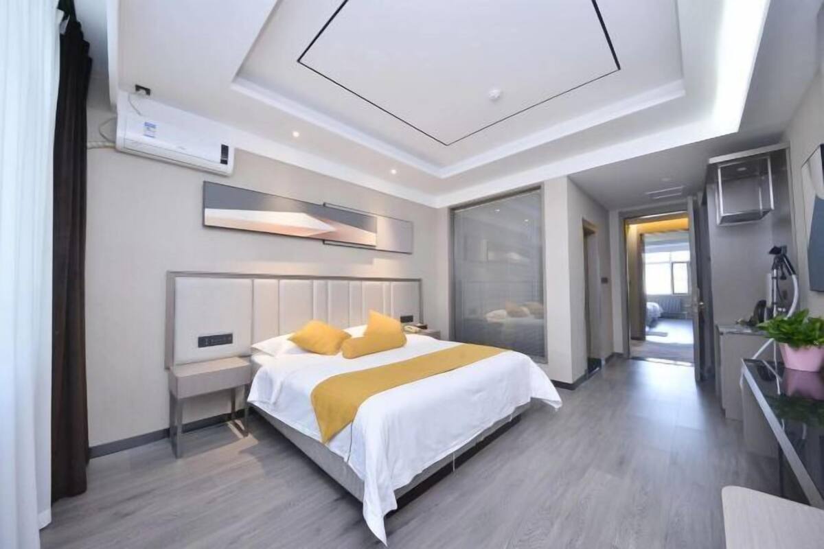 Une chambre d’hôtel moderne, équipée d’un lit, d’une table de chevet et d’un grand miroir.