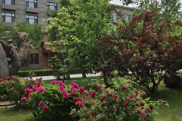 A landscaped garden with flowering plants and trees, a pathway, and a building in the background. - Konggang Hotel (Harbin Airport International Terminal) (Harbin)