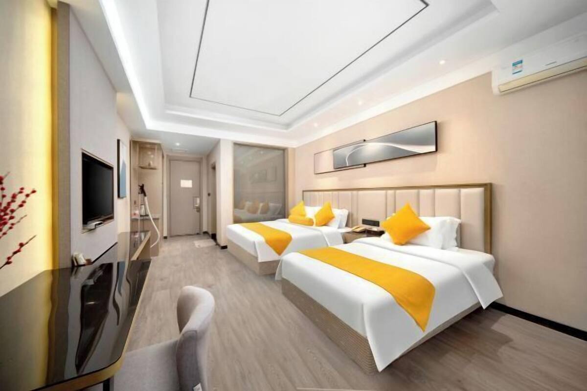 Une chambre d’hôtel moderne équipée de deux lits, d’un téléviseur à écran plat, d’un bureau et d’un grand miroir.