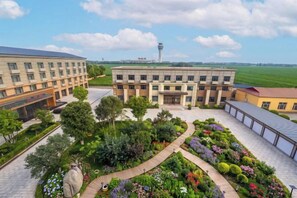 A courtyard with a central building, surrounded by greenery and a clear sky.