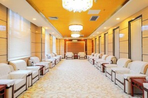 A hotel conference room with rows of seating, a chandelier, and a carpeted floor. - Yijiang Hotel (Wusu)