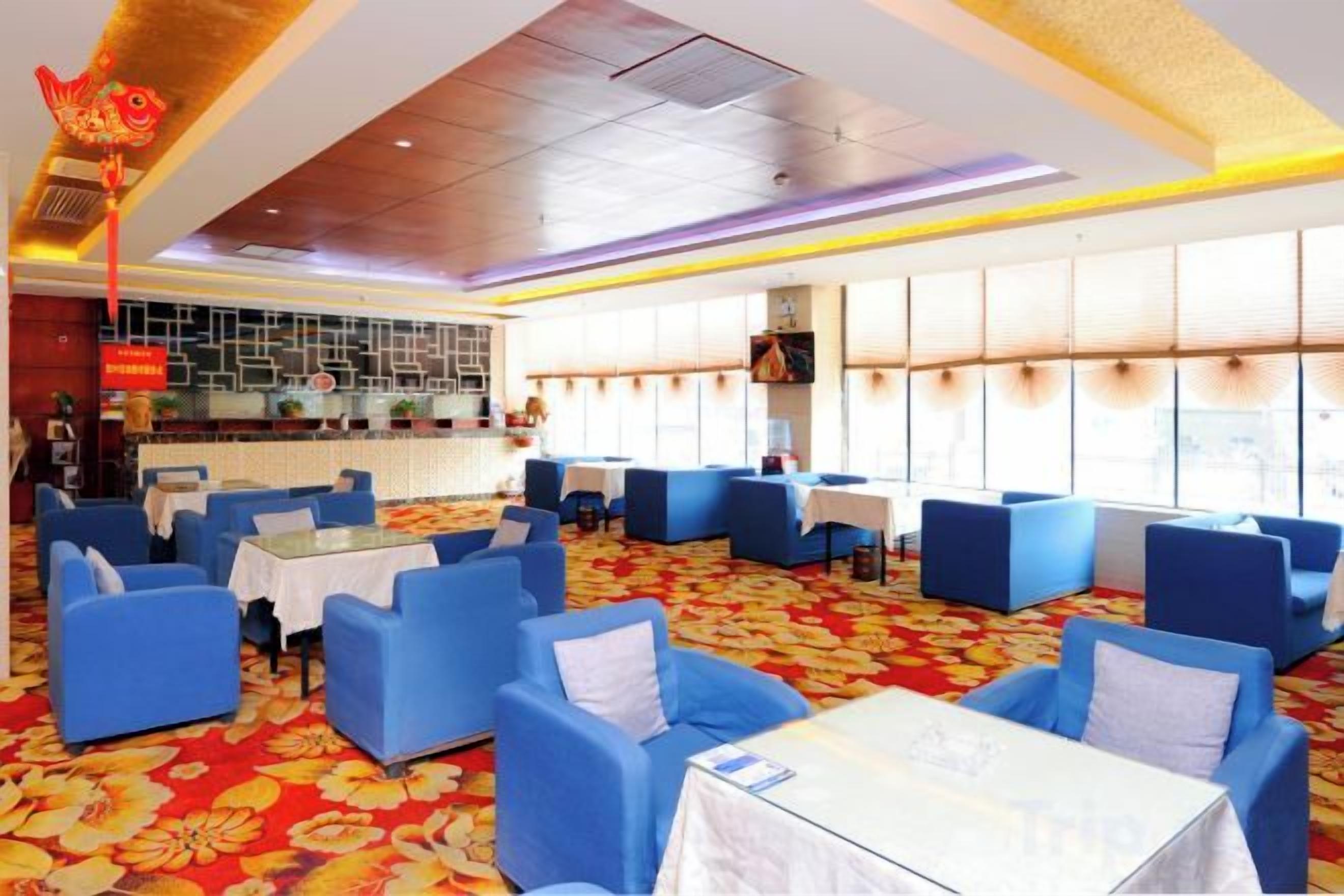 Un restaurante con asientos azules, techo de azulejos y alfombra roja.