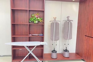 Een kamer met een houten schapunit, een strijkplank en twee massagestoelen.