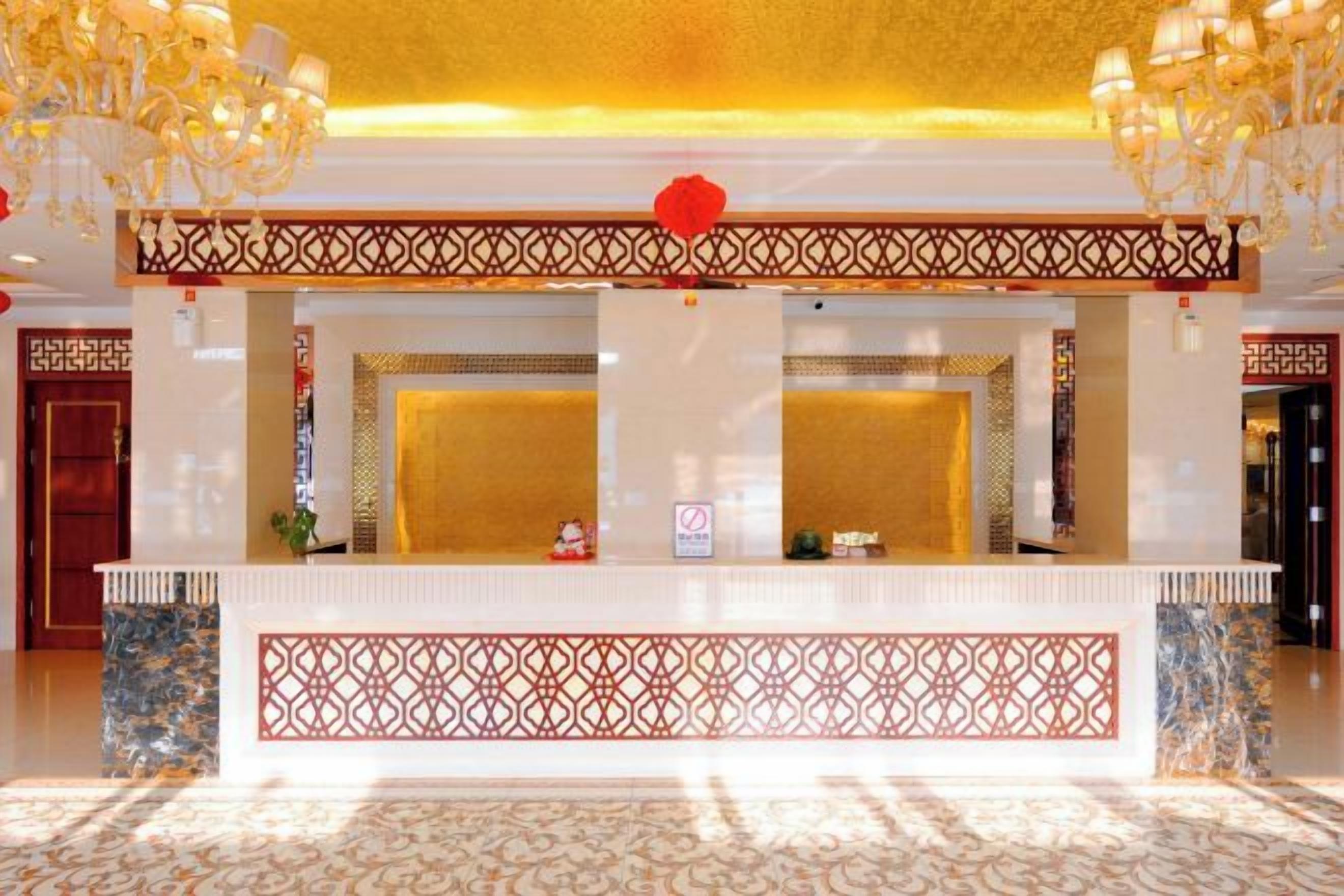 A reception area with a white reception desk, decorative screens, and chandeliers.