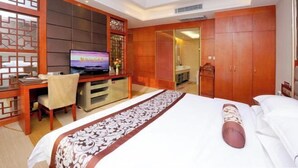 A hotel room with a bed, a desk with a TV, a wardrobe, and a sliding door leading to a bathroom. - Yijiang Hotel (Wusu)