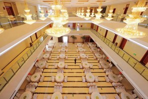 A hotel lobby with a central open space, multiple seating areas, and a grand chandelier. - Yijiang Hotel (Wusu)
