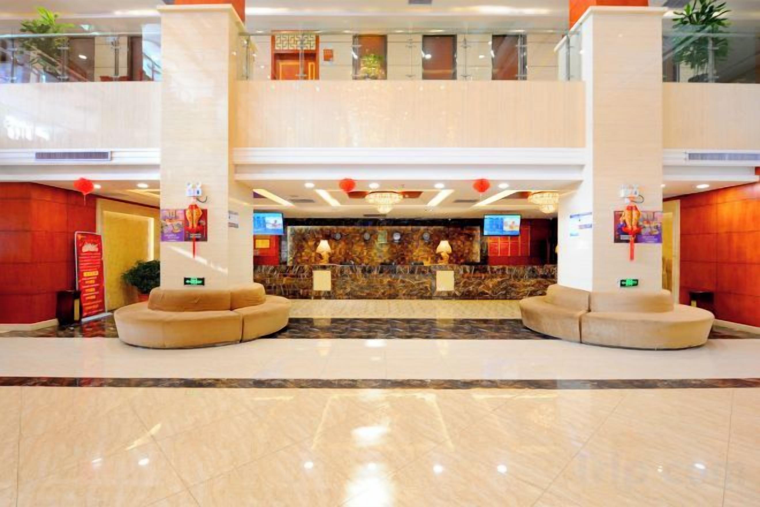 Un hall d’hôtel comprenant un comptoir d’accueil, un espace salon et un plafond haut orné d’un éclairage décoratif.