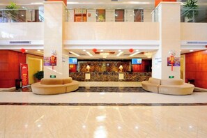 A hotel lobby with a reception desk, seating area, and a high ceiling with decorative lighting. - Yijiang Hotel (Wusu)