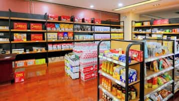 A store interior with shelves stocked with various products, a checkout counter, and a display of bottled water.