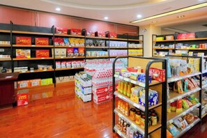 A store interior with shelves stocked with various products, a checkout counter, and a display of bottled water.