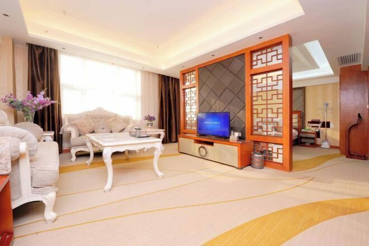A modern living room with a sofa, a coffee table, a TV, and a decorative screen.